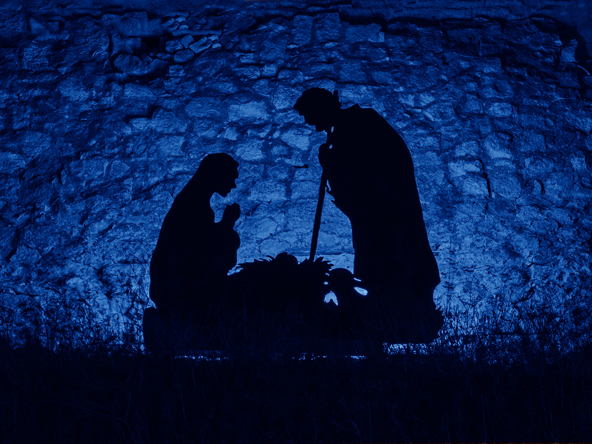 Christmas man nativity scene installation on the theme of the birth of Jesus Christ, shadow and silhouette. Street decoration on eve of Xmas. Toned image with trend color of 2020 year Classic blue