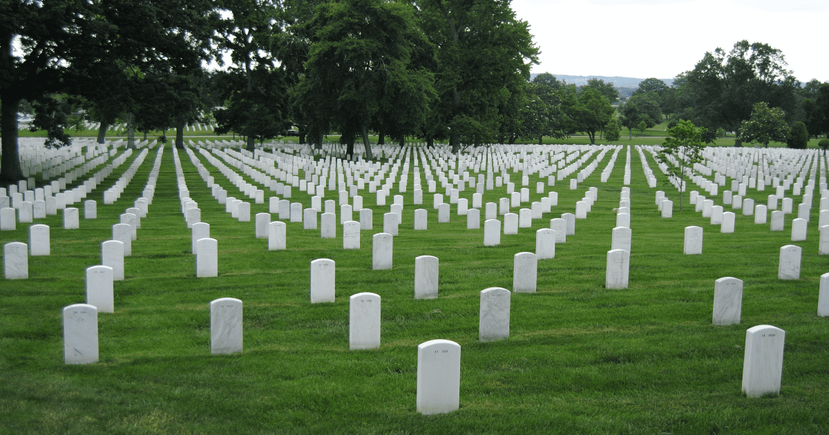 a grassy cemetery full of rows of white, symmetrical gravestones