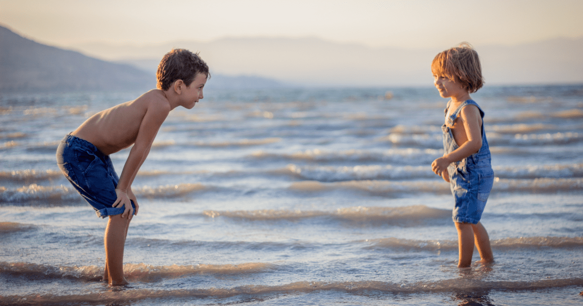 two boys play in the ocean at a beach