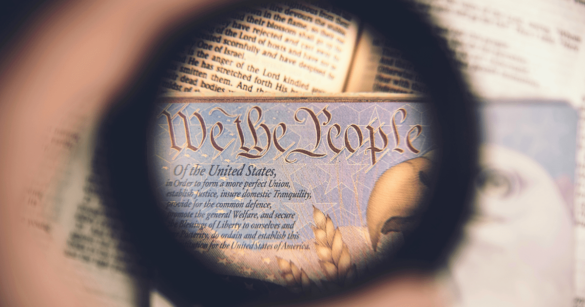 looking through a magnifying glass lens at the first words of the Declaration of Independence, "We the People"